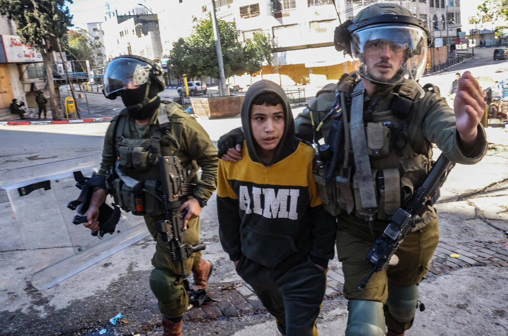 Members of the Israeli security forces arrest a young boy during confrontations with Palestinian demonstrators in the centre of the West Bank town of Hebron, on January 21, 2022. (Photo by HAZEM BADER / AFP)