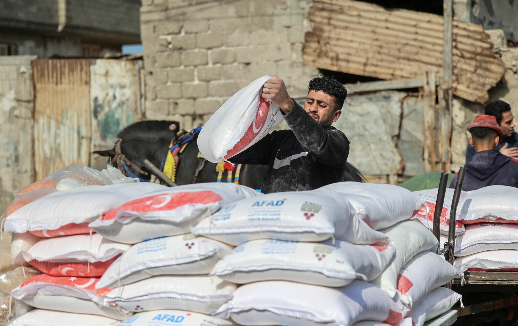 Palestinians collect food aid at a distribution center run by the United Nations Relief and Works Agency (UNRWA), in Gaza City, on March 1, 2022. (Photo by MOHAMMED ABED / AFP)