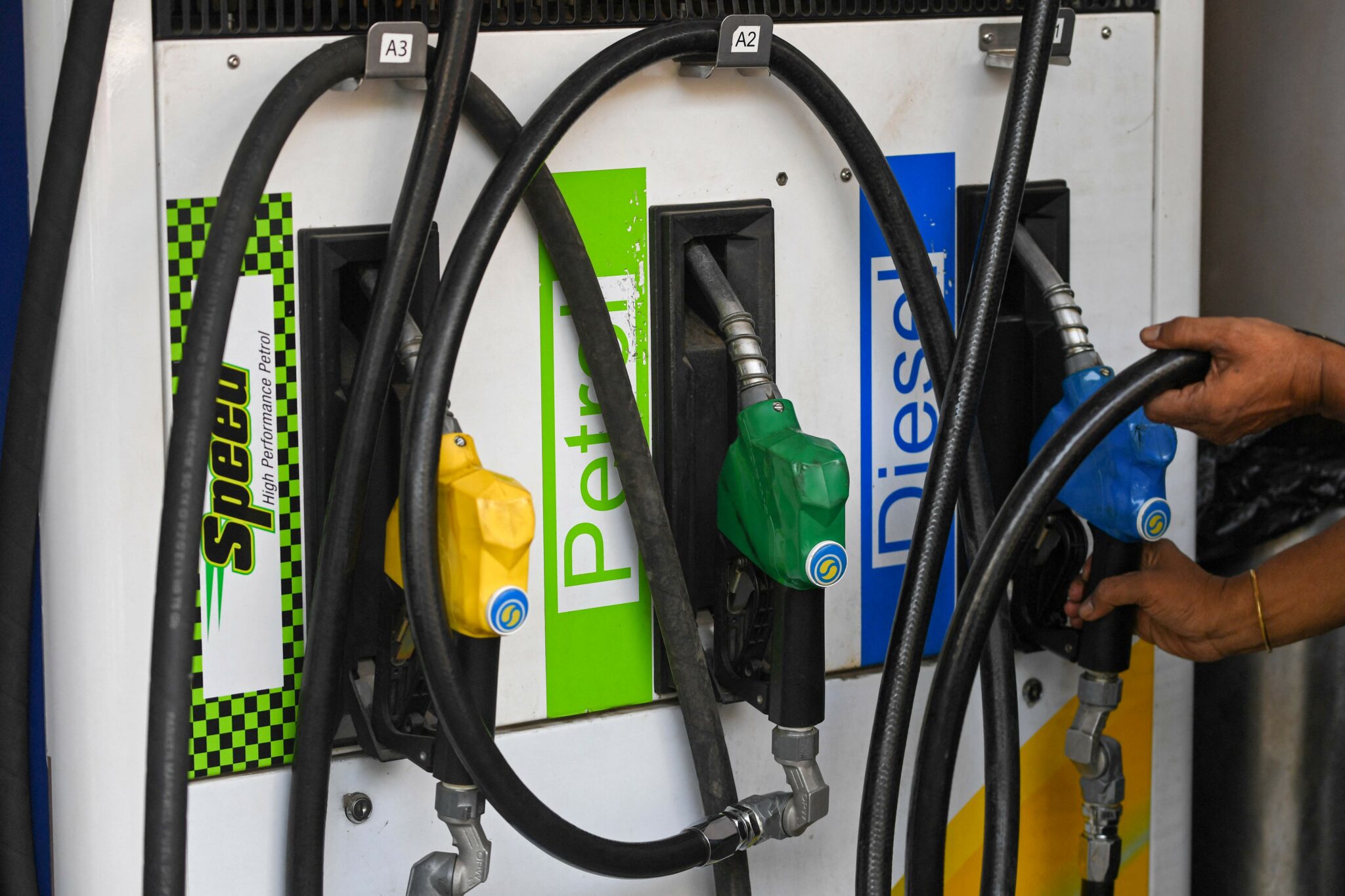 An attendant puts back a nozzle after filling petrol in a vehicle at a fuel station in Mumbai on March 7, 2022. (Photo by Indranil MUKHERJEE / AFP)