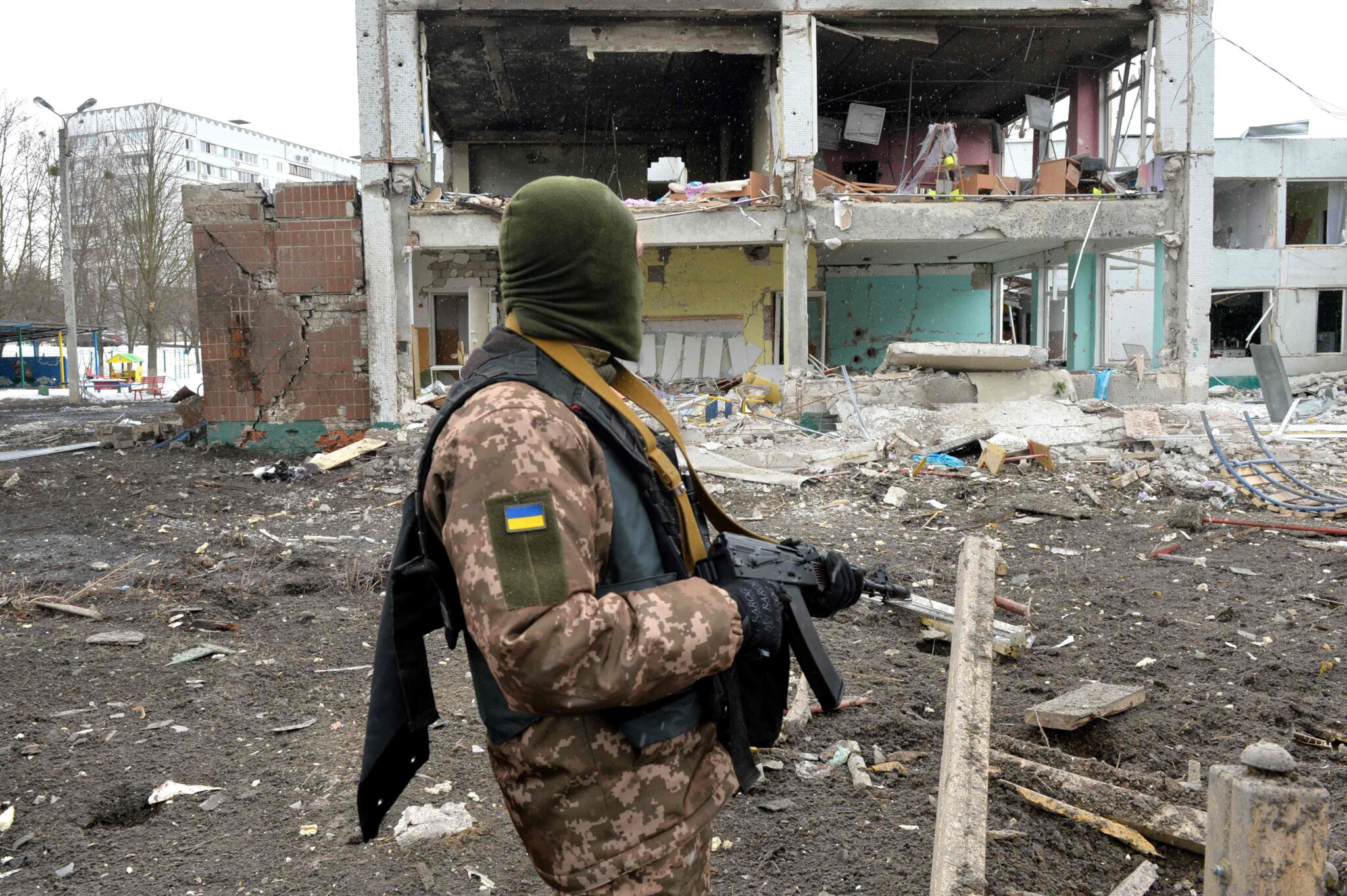 A member of the Ukrainian Territorial Defence Forces looks at destructions following a shelling in Ukraine's second-biggest city of Kharkiv on March 8, 2022. On the 13th day of the war, the UN said the number of refugees flooding across Ukraine's borders had passed two million. (Photo by Sergey BOBOK / AFP)