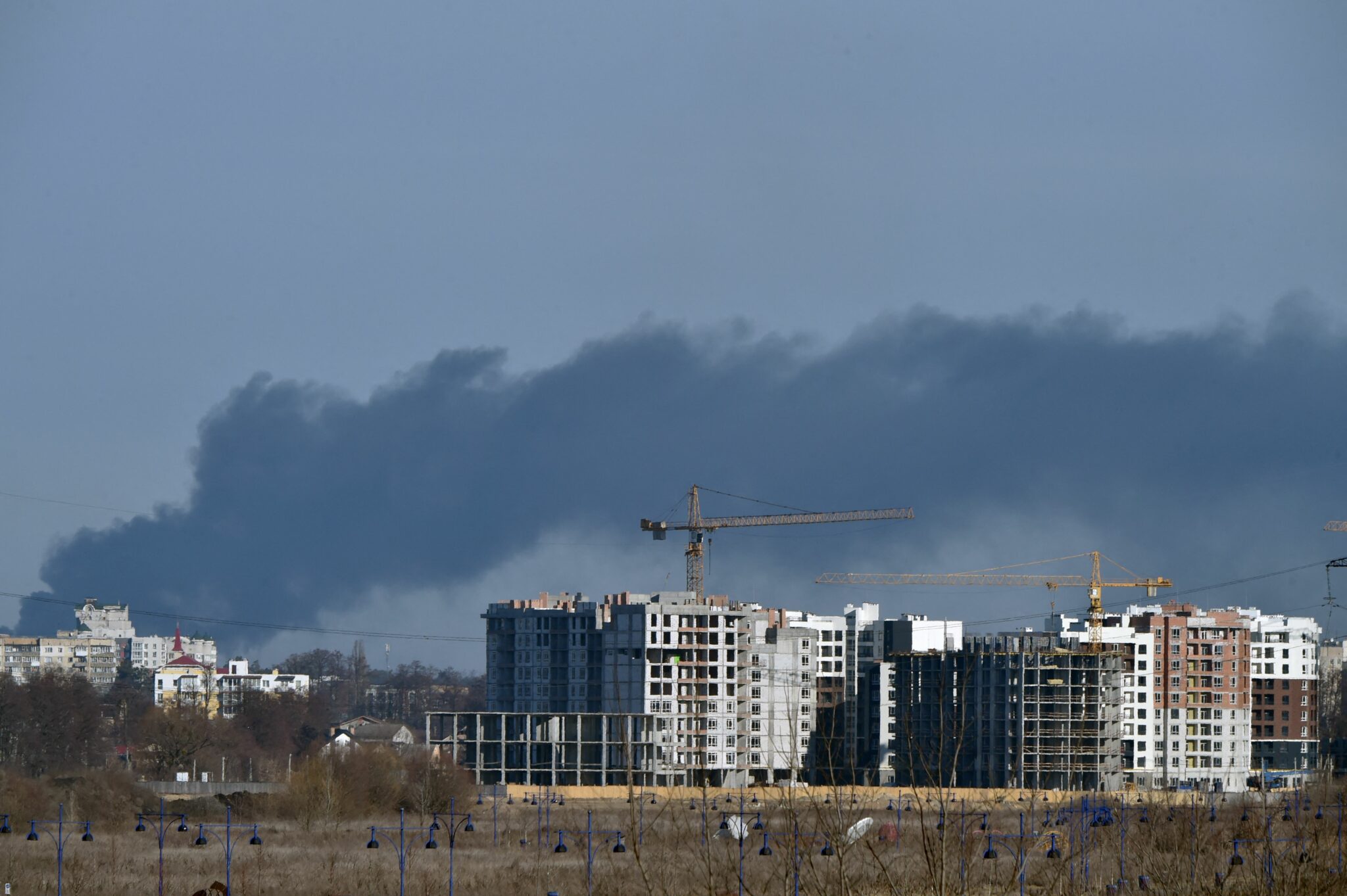 This photograph taken on March 12, 2022 shows smoke rising over Irpin, north of Kyiv. Russian forces stepped up the pressure on Kyiv on March 12, 2022. The northwest suburbs of the capital, including Irpin and Bucha, have already endured days of heavy bombardment while Russian armoured vehicles are advancing on the northeastern edge. (Photo by Sergei SUPINSKY / AFP)