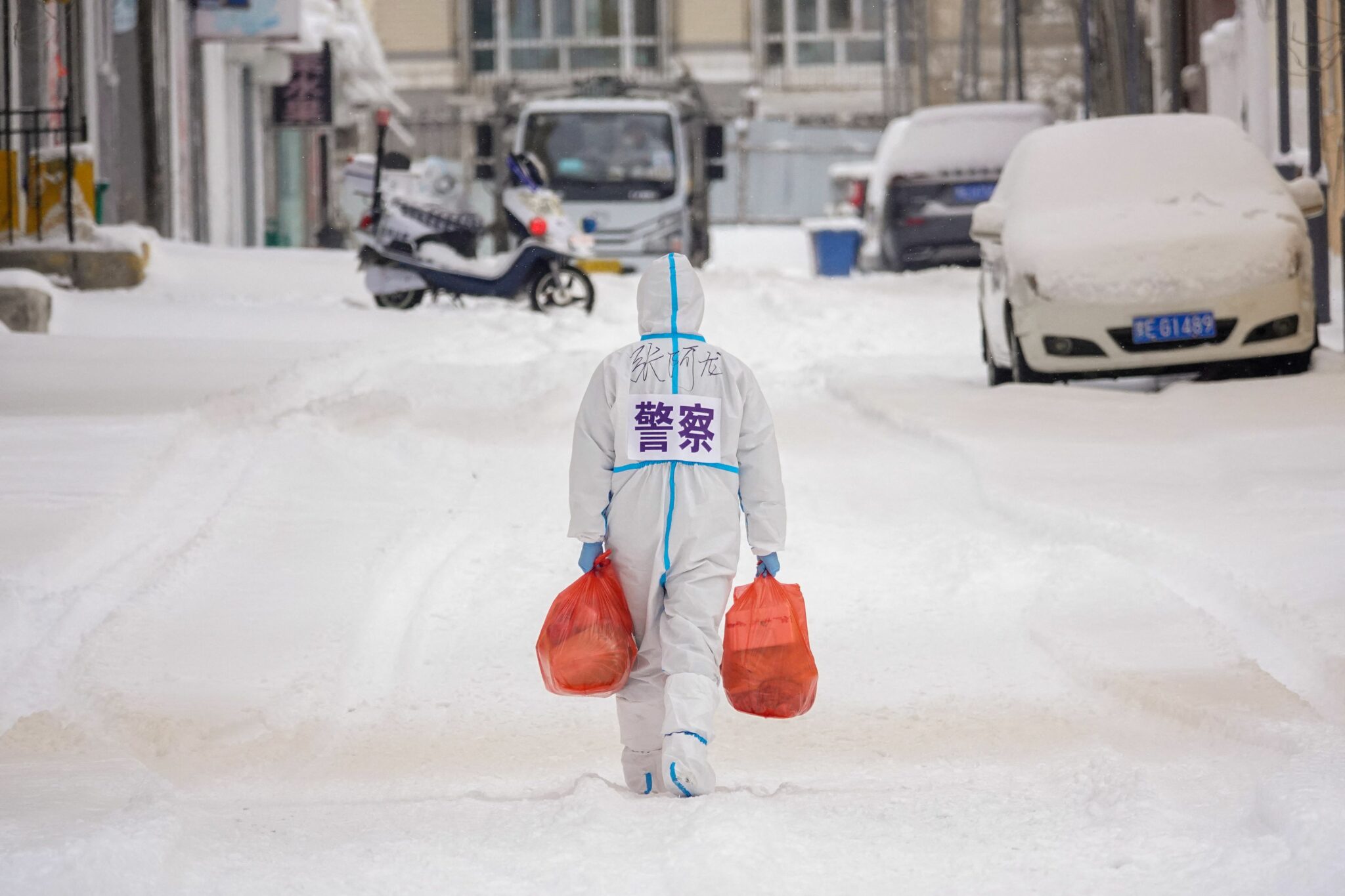 A police officer wearing personal protective equipment (PPE) carries food and daily supplies that will be distributed to residents at a restricted residental area due to the spread of the Covid-19 coronavirus in Manzhouli in China's northern Inner Mongolia region on March 15, 2022. China OUT (Photo by AFP)