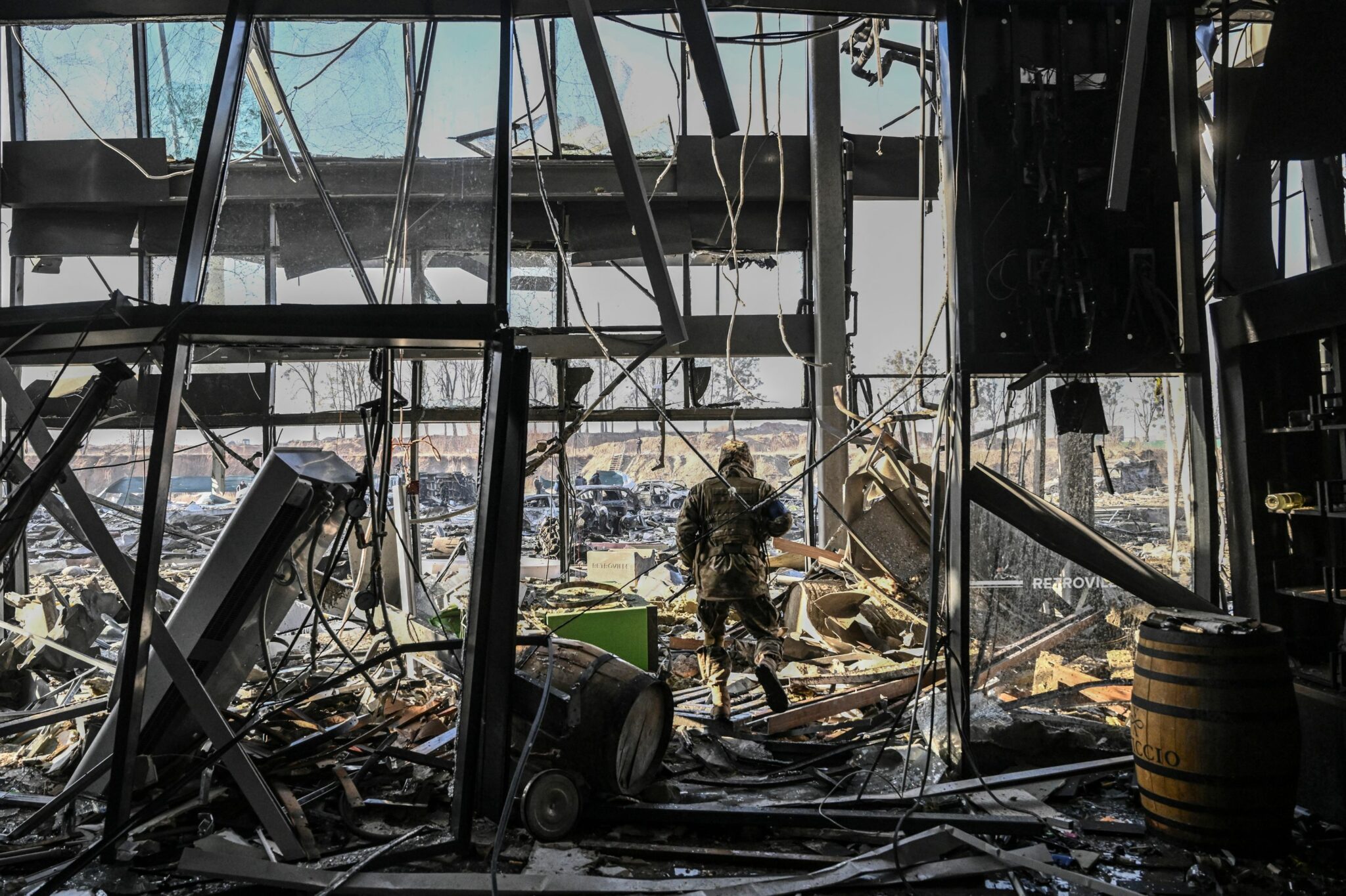 A Ukranian serviceman walks between derbis inside the the Retroville shopping mall after a Russian attack on the northwest of the capital Kyiv on March 21, 2022. At least six people were killed in the overnight bombing of a shopping centre in the Ukrainian capital Kyiv, an AFP journalist said, with rescuers combing the wreckage for other victims. The 10-storey building was hit by a powerful blast that pulverised vehicles in its car park and left a crater several metres (yards) wide. (Photo by ARIS MESSINIS / AFP)