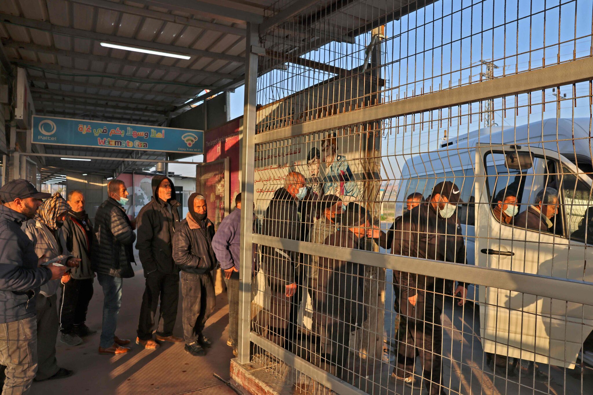 Palestinian workers enter a mini van at the last station in Beit Hanun in the northern Gaza Strip, before reaching Israel through the Erez crossing to work, on February 23, 2022. Gaza, a Palestinian territory of some 2.3 million people under Israeli-blockade since 2007, suffers from an unemployment rate above 50 percent, where even those with post-graduate degrees can struggle to get by. And Israeli work permits have become a rarity for Palestinians in the last decade or so -- making the few on offer seem like gold dust. (Photo by MOHAMMED ABED / AFP)