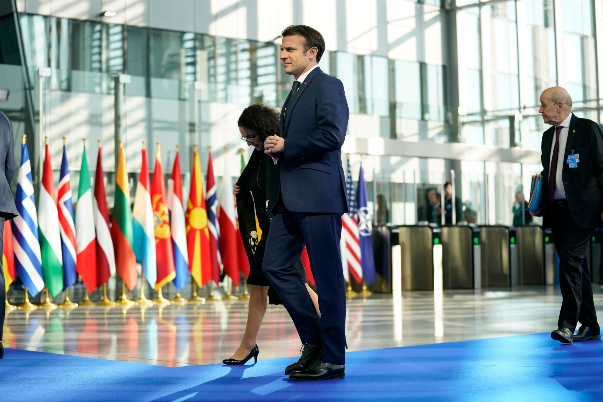 France's President Emmanuel Macron (C) and French Foreign Affairs Minister Jean-Yves Le Drian (R) arrive for an extraordinary NATO summit at NATO Headquarters in Brussels on March 24, 2022. (Photo by Evan Vucci / POOL / AFP)