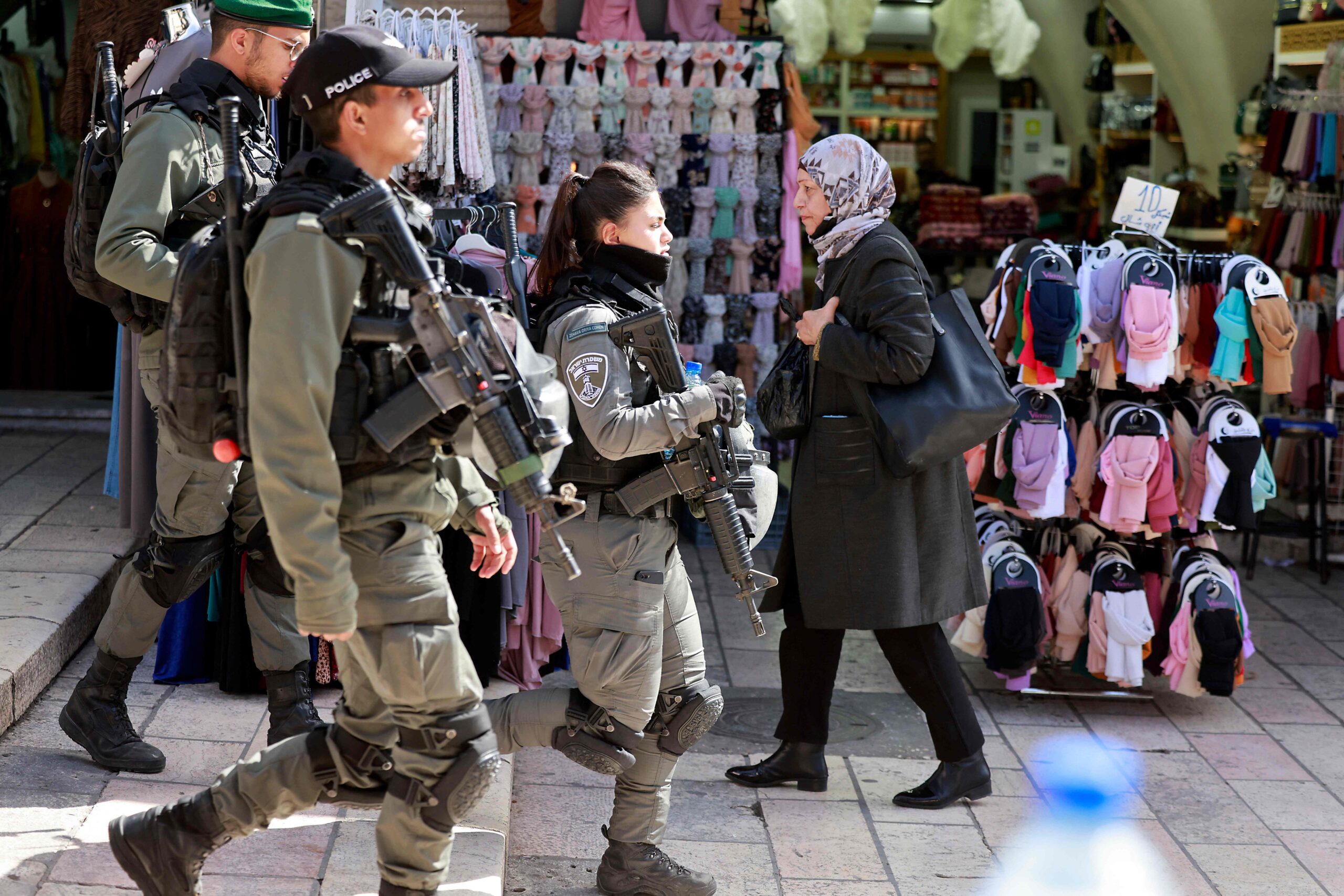 A Palestinian woman walks past Israeli security forces patrolling Jerusalem's Old City on March 31, 2022. (Photo by Menahem KAHANA / AFP)