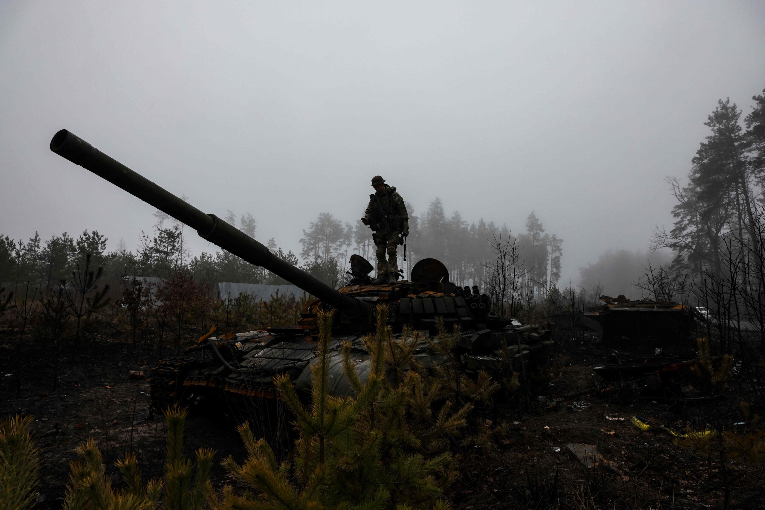 An Ukranian soldier takes pictures of a Russian tank, in the outskirts of Kyiv, on April 1, 2022, amid Russian invasion of Ukraine. (Photo by RONALDO SCHEMIDT / AFP)