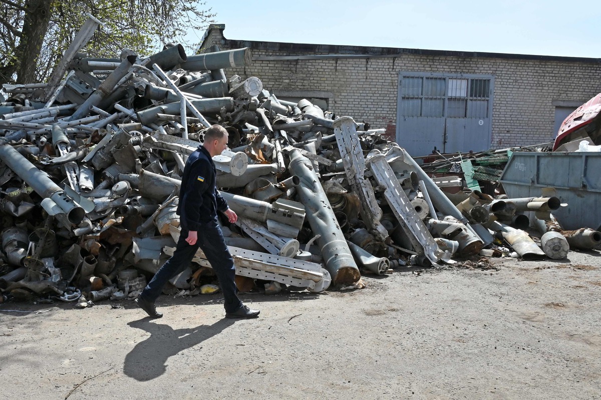 TOPSHOT - A member of the State Emergency Service of Ukraine walks past a pile of missile remains, collected in the city after shellings in Kharkiv on April 25, 2022, amid the Russian invasion of Ukraine. (Photo by SERGEY BOBOK / AFP)