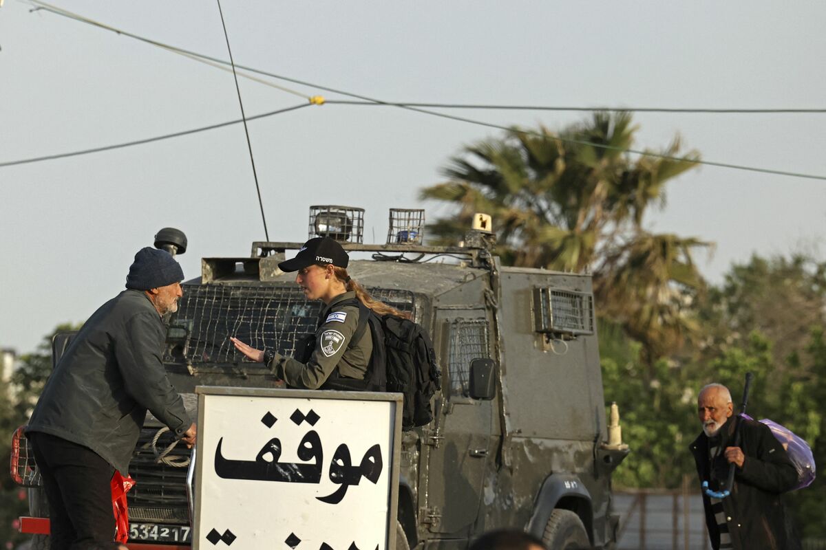 A member of Israeli security forces stands guard as Palestinians arrive in large numbers to the Qalandia checkpoint in the occupied West Bank, to reach Jerusalem's Al-Aqsa Mosque to mark Laylat al Qadr during the Muslim fasting month of Ramadan on April 27, 2022. Laylat al-Qadr (Night of Destiny) is according to tradition the night in which the holy Koran was first revealed to the Prophet Mohammed. (Photo by ABBAS MOMANI / AFP)