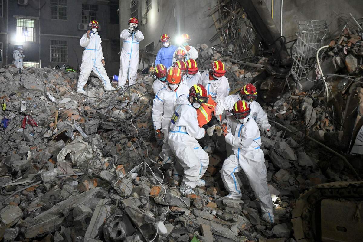 This photo taken early on May 5, 2022 shows rescuers carrying a survivor out of a collapsed six-storey building in Changsha, central Chinas Hunan province. Fifty-three people died in a building collapse in central China, authorities said on May 6, announcing the end of the rescue mission in a disaster which has been blamed on illegal construction. - China OUT (Photo by CNS / AFP)