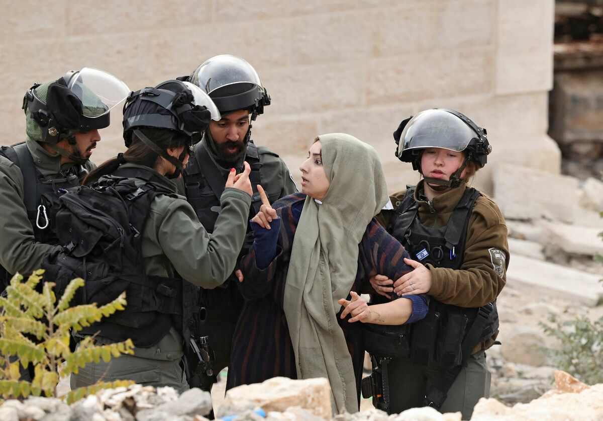 A Palestinian woman is escorted by Israeli security forces as she tries to stop the demolition of her home, located within the "Area C" of the occupied West Bank, where Israel retains full control over planning and construction, in the occupied West Bank town of Hebron on December 28, 2021. (Photo by HAZEM BADER / AFP)