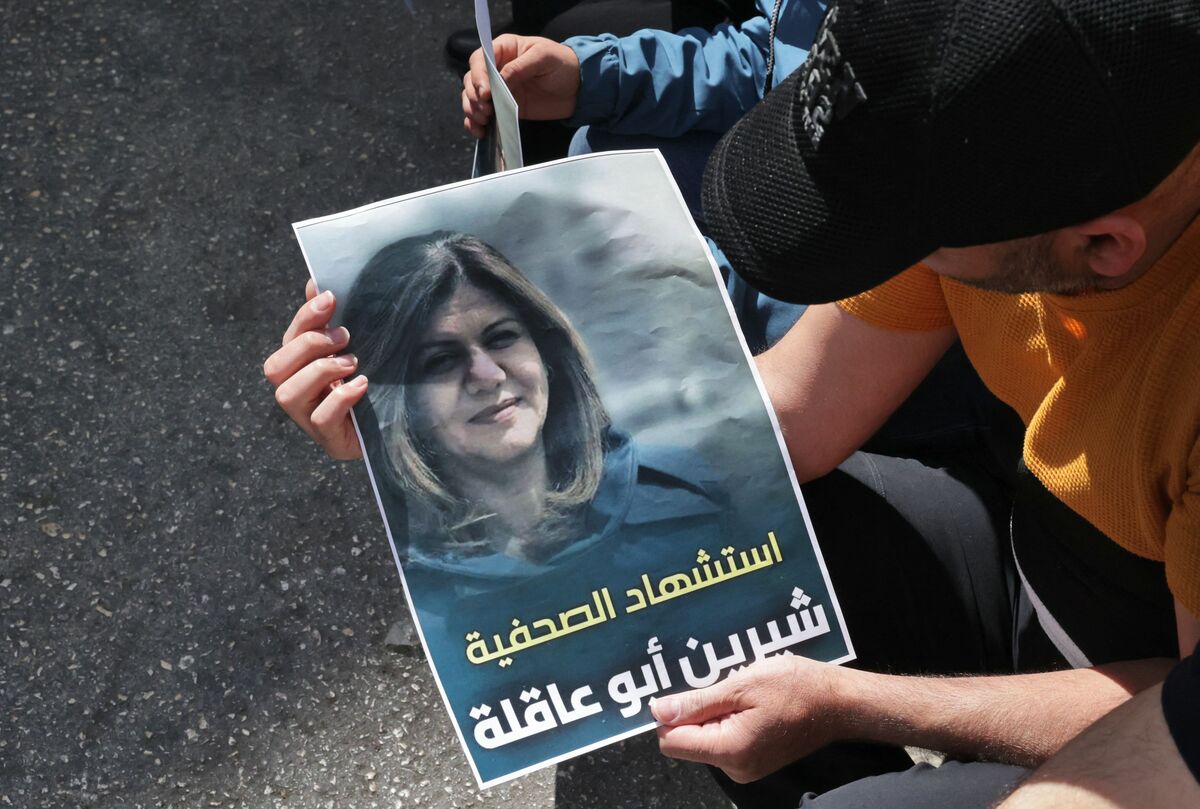 Palestinians hold a poster displaying veteran Al Jazeera journalist Shireen Abu Aqleh, who was, according to the network, shot dead by Israeli troops as she covered a raid on the West Bank's Jenin refugee camp on May 11, 2022, in the West Bank city of Hebron. The poster reads in Arabic, "the Martyrdom of Journalists Shireen Abu Aqleh". (Photo by HAZEM BADER / AFP)