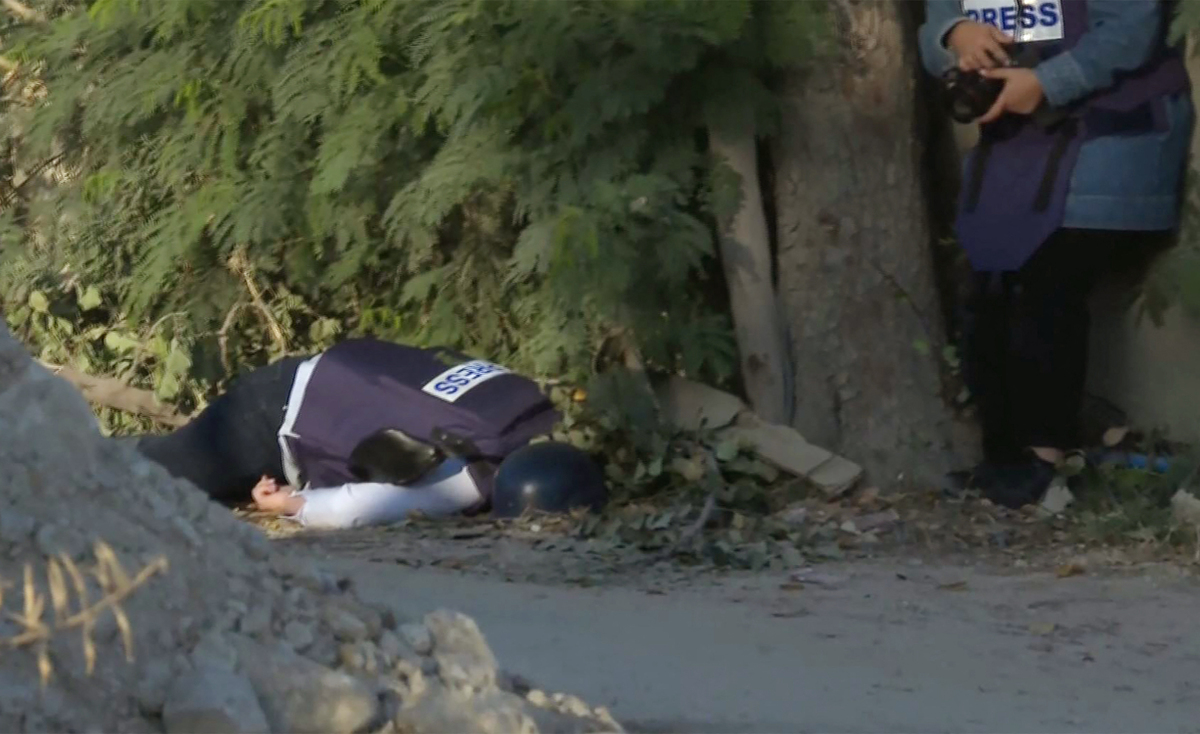 An image grab from footage distributed by the Doha-based Al-Jazeera TV shows a reporter reacting (R) as the channel's veteran journalist Shireen Abu Aqleh is seen on the ground after being shot in the face in Jenin in the occupied West Bank on May 11, 2022. Abu Aqleh, 51, a prominent figure in the channel's Arabic news service was shot dead by Israeli troops early in the morning as she covered a raid on Jenin refugee camp in the occupied West Bank, according to Al-Jazeera. The Qatari news channel said its journalist had been shot dead "deliberately" and "in cold blood" by Israeli troops but Israeli Prime Minister Naftali Bennett said it was likely Palestinian gunfire had killed the reporter. - RESTRICTED TO EDITORIAL USE - MANDATORY CREDIT "AFP PHOTO / Al-Jazeera" - NO MARKETING NO ADVERTISING CAMPAIGNS - DISTRIBUTED AS A SERVICE TO CLIENTS (Photo by AL JAZEERA / AFP) / RESTRICTED TO EDITORIAL USE - MANDATORY CREDIT "AFP PHOTO / Al-Jazeera" - NO MARKETING NO ADVERTISING CAMPAIGNS - DISTRIBUTED AS A SERVICE TO CLIENTS