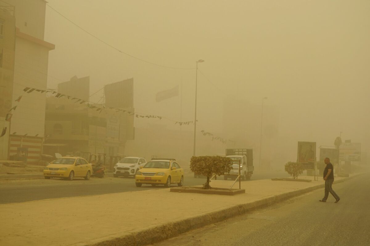 A man crosses a main road during a Spring sandstorm in the Iraqi capital Baghdad on May 5, 2022. Iraq is yet again covered in a thick sheet of orange as it suffers the latest in a series of dust storms that have become increasingly common. Iraq was hammered by a series of such storms in April, grounding flights and leaving dozens hospitalised with respiratory problems. (Photo by Sabah ARAR / AFP)