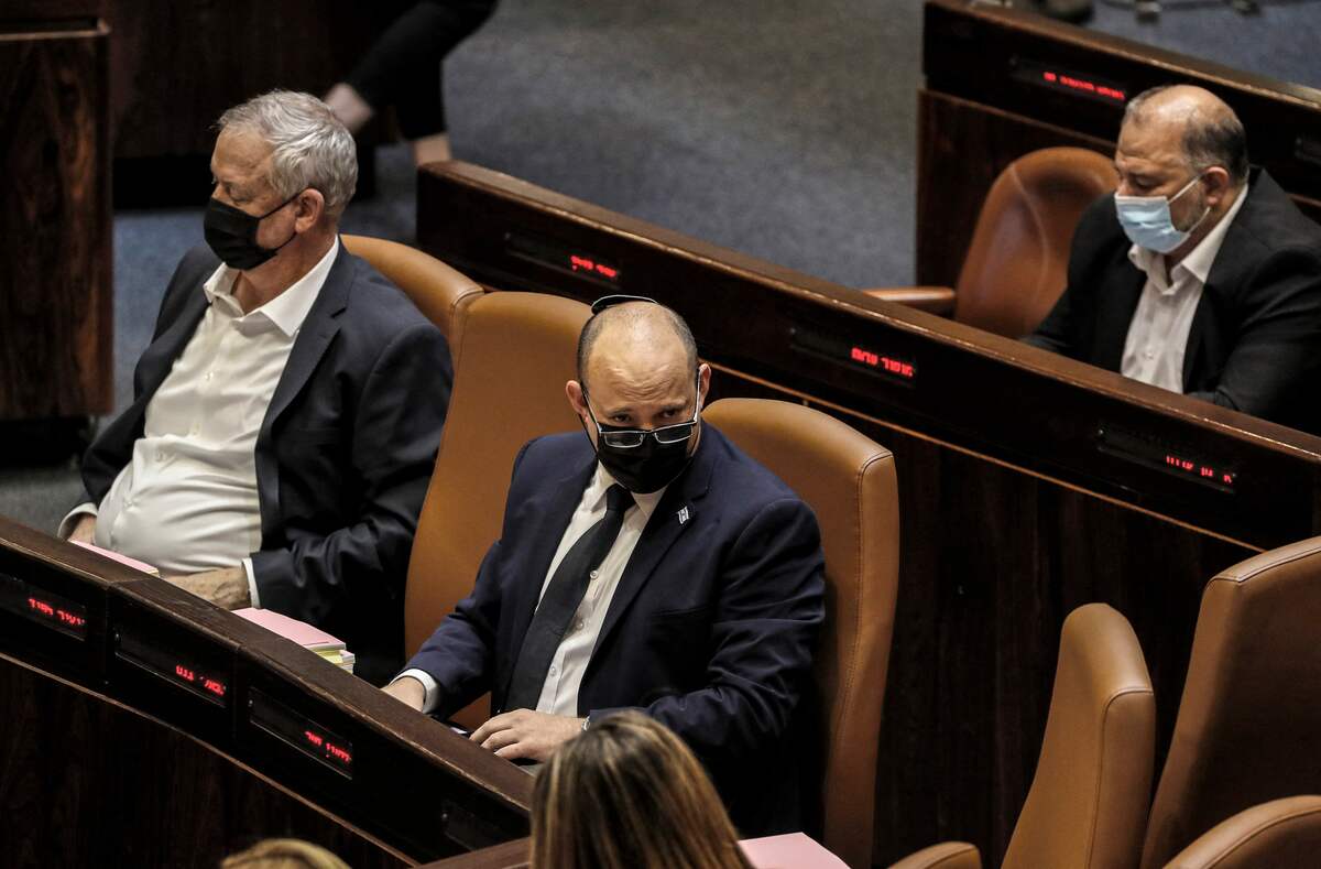 Israeli Prime Minister Naftali Bennett (C) looks on while seated next to Defence Minister Benny Gantz (L) and Arab-Israeli lawmaker Mansour Abbas (R) of the conservative Islamic Raam party, during a plenum session and vote on the state budget at the assembly hall in the Knesset (Israeli parliament), in Jerusalem on November 3, 2021. (Photo by AHMAD GHARABLI / AFP)