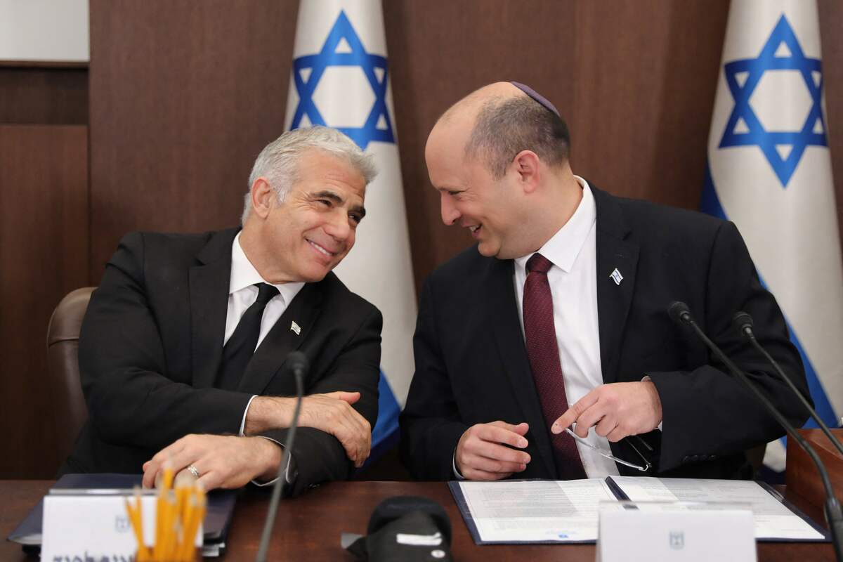 Israeli Prime Minister Naftali Bennett (R) speaks with Foreign Minister Yair Lapid (L) during a cabinet meeting at the Prime minister's office in Jerusalem, on June 19, 2022. (Photo by Abir SULTAN / POOL / AFP)