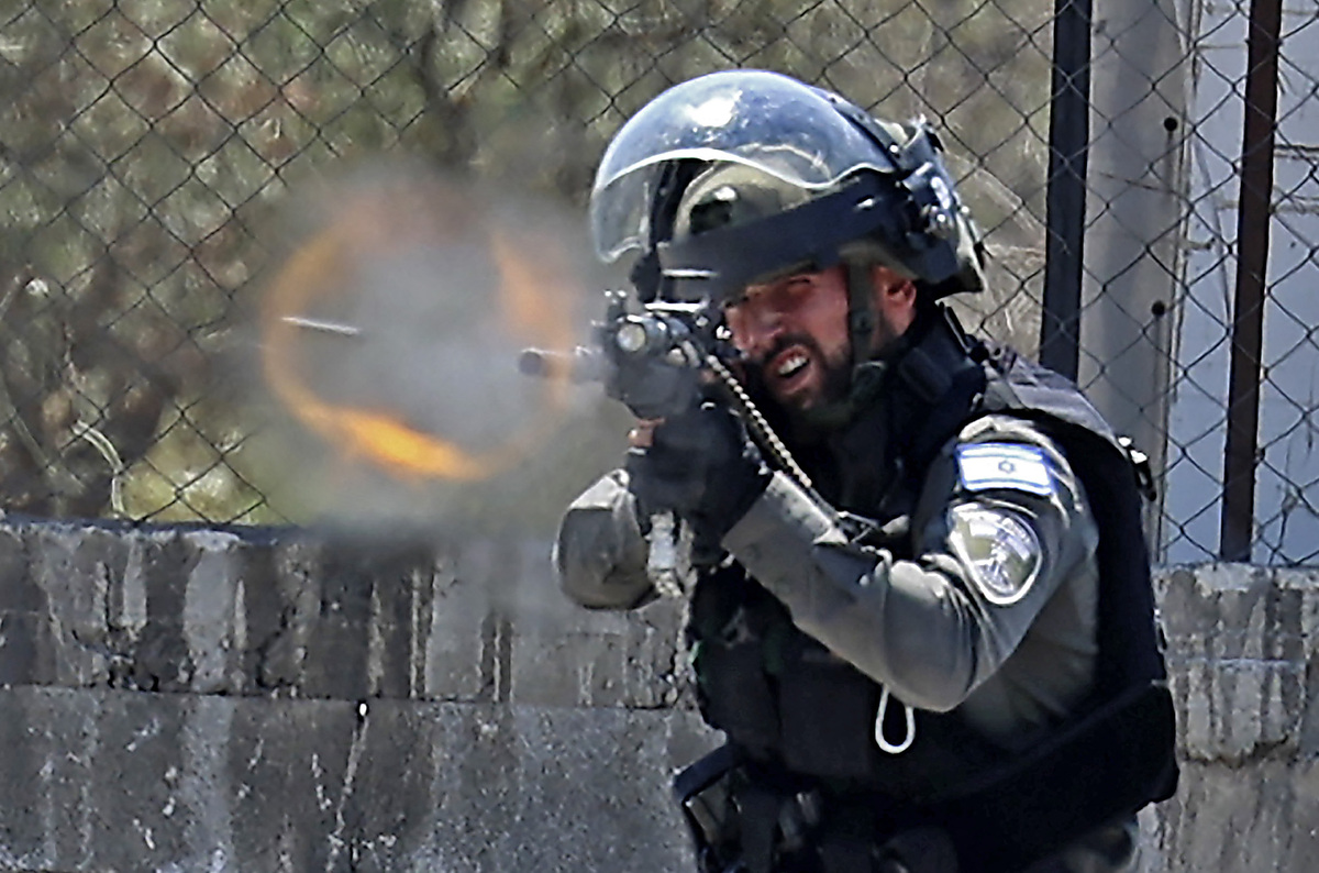 A member of the Israeli border police fires rubber bullets toward Palestinian demonstrators, during clashes with them in the West Bank town of Beita south of Nablus, on June 3, 2022. (Photo by JAAFAR ASHTIYEH / AFP)