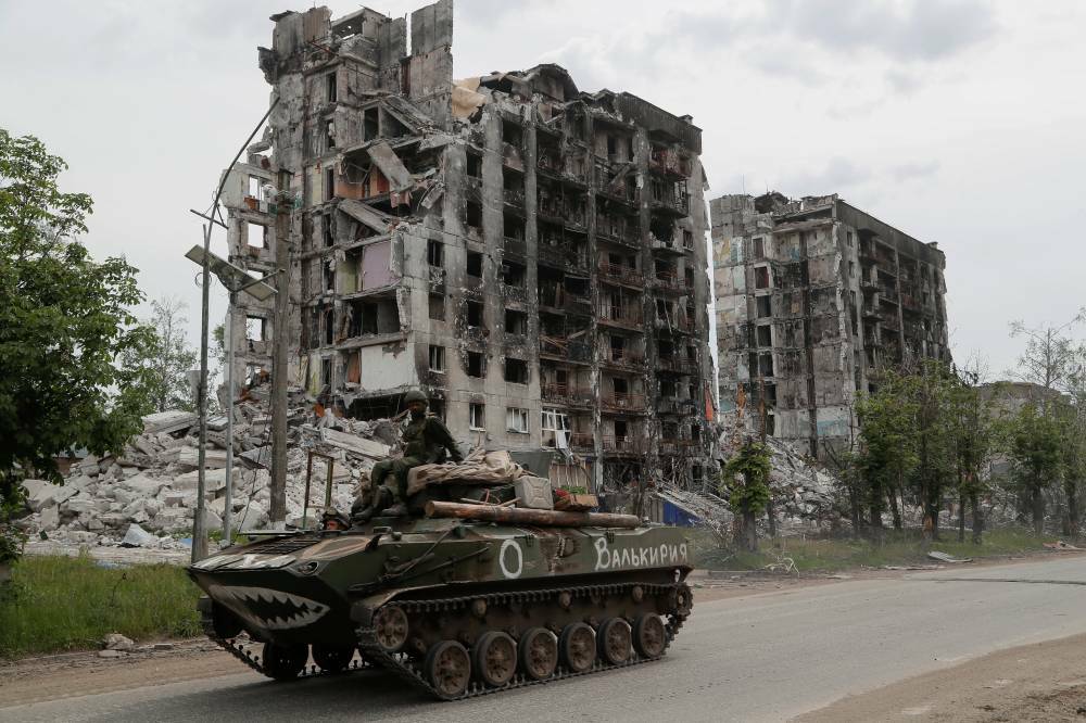 Service members of pro-Russian troops drive an armoured vehicle along a street past a destroyed residential building during Ukraine-Russia conflict in the town of Popasna in the Luhansk Region, Ukraine May 26, 2022. The writing on the vehicle reads: "Valkyrie". REUTERS/Alexander Ermochenko