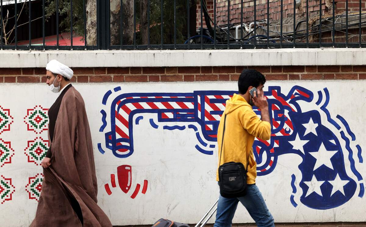 (FILES) In this file photo taken on March 12, 2022 Iranians walk past an anti-US mural on a wall of the former United States embassy in the capital Tehran. The United States confirmed on June 2, 2022 it would join Europeans in backing a resolution urging Iran to cooperate with the UN nuclear watchdog, despite warnings from Tehran that the move could scuttle diplomacy. (Photo by ATTA KENARE / AFP)