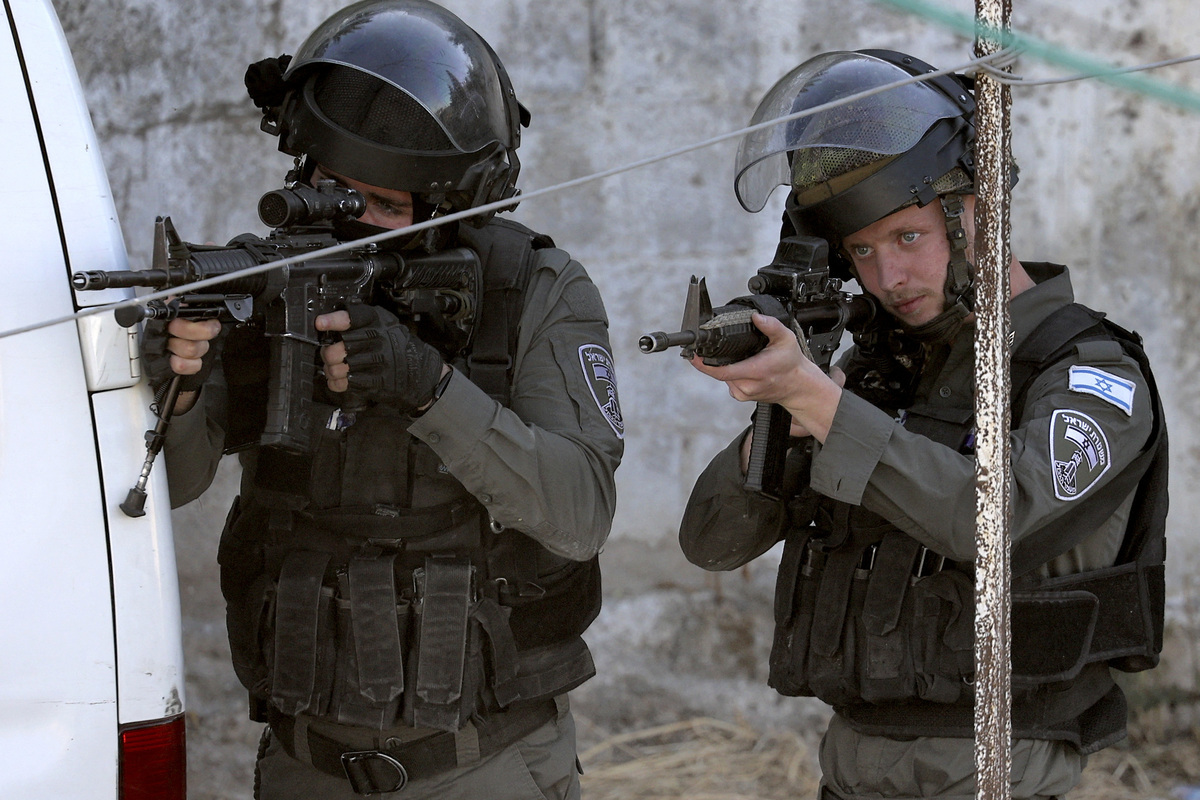 Israeli border guards take aim during a raid at house in the town of Rummanah, near the flashpoint town of Jenin in the occupied West Bank on May 8, 2022, reportedly the home of Palestinian Subhi Imad Abu Shukair, suspected of carrying out a fatal axe attack in the central city of Elad two days earlier. Two Palestinians suspected of killing three Israelis in an axe attack in Elad were arrested after a more than two day manhunt, the security services said. (Photo by JAAFAR ASHTIYEH / AFP)