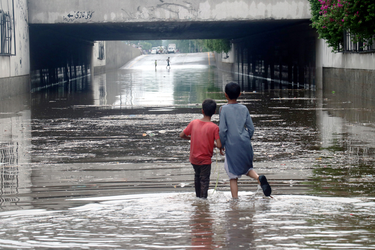 (220722) -- LAHORE, July 22, 2022 (Xinhua) -- Children wade through flood water after heavy monsoon rains in Lahore, Pakistan, July 21, 2022. At least 282 people have been killed and 211 others injured in separate rain-related incidents in Pakistan since June 14 as heavy downpours continued to lash the country, the National Disaster Management Authority (NDMA) said. (Photo by Jamil Ahmed/Xinhua)