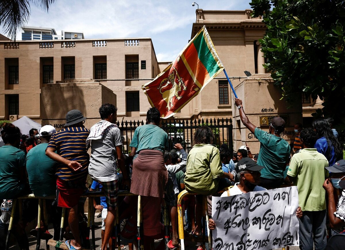 A person waves a Sri Lankan flag as demonstrators shout slogans demanding the immediate release from police custody of the demonstrators who were obstructing an entrance to Sri Lanka's Presidential Secretariat, amid the country's economic crisis, in Colombo, Sri Lanka, June 20, 2022. REUTERS/Dinuka Liyanawatte TPX IMAGES OF THE DAY