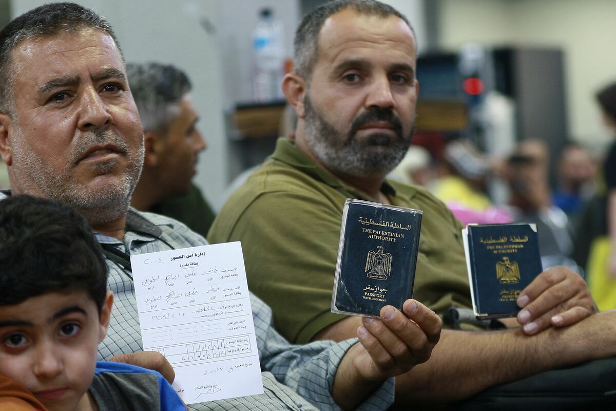 Passengers, holding their Palestinian passports, sit in a waiting room on the Jordanian side of the King Hussein Bridge (also known as Allenby Bridge) crossing between the West Bank and Jordan on July 19, 2022. The border crossing, which serves as a border crossing between Israel and Jordan mainly for the Palestinians and foreign tourists, has witnessed an issue with crowding with passengers stuck on the Jordanian side. (Photo by Khalil MAZRAAWI / AFP)