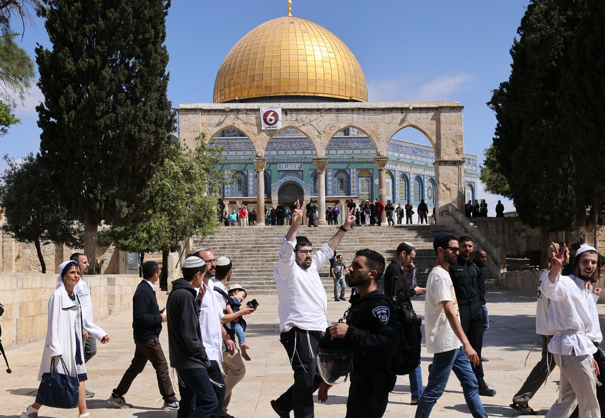 Israeli police accompany a group of Jewish visitors past the Dome of the Rock mosque at the al-Aqsa mosque compound in the Old City of Jerusalem on May 5, 2022. Clashes erupted between Israelis and Palestinians at Jerusalem's Al-Aqsa mosque compound, after a 10-day cooling of tensions at the holy site, Israeli police said. The Israeli police said they had repelled "dozens of rioters" who had been "throwing stones and other objects" at the security forces. (Photo by AHMAD GHARABLI / AFP)