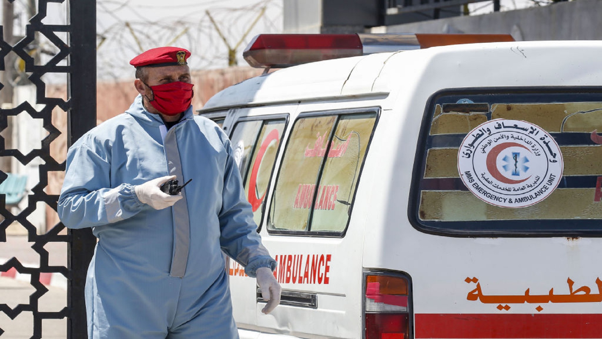 An ambulance drives past a member of the security forces loyal Gaza's Islamist rulers Hamas, wearing personal protective equipment as a precaution against the coronavirus (COVID-19) pandemic, at the Rafah border crossing with Egypt, in the southern Gaza Strip on April 13, 2020, after the crossing was temporarily reopened for four days. - The Palestinian embassy in Egypt announced that Egyptian authorities temporarily reopened the border crossing with the Palestinian enclave today, and for four days until April 16, to help facilitate the movement of Palestinians wishing to return to the Gaza Strip. (Photo by SAID KHATIB / AFP) (Photo by SAID KHATIB/AFP via Getty Images)