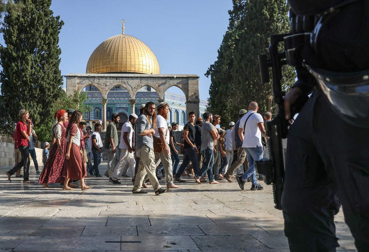 Israeli security forces protect a group of Jewish settler visitors as they walk past the Dome of the Rock mosque at the Al-Aqsa compound in Jerusalem, on August 7, 2022, amidst hightened tensions between Israel and Palestinian militants in the Gaza strip. (Photo by AHMAD GHARABLI / AFP)