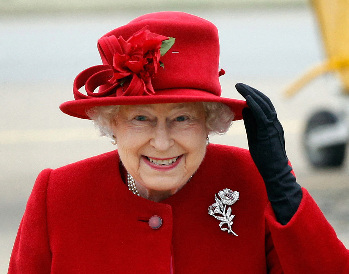 (FILES) In this file photo taken on April 01, 2011 Britain's Queen Elizabeth II holds on to her hat in high winds as she arrives for a visit to RAF Valley in Anglesey, Wales. Brightly coloured outfits, a matching hat and a pristine pair of gloves: Queen Elizabeth II's look was instantly recognisable and a self-created uniform styled to suit her role. During her reign, the monarch tried out every shade in the colour chart, from canary yellow to lime green, fuchsia and navy blue. Her inimitable style was developed over the decades by aides and designers, starting with Norman Hartnell, who created her wedding dress when she married Prince Philip in 1947. (Photo by Christopher Furlong / POOL / AFP)