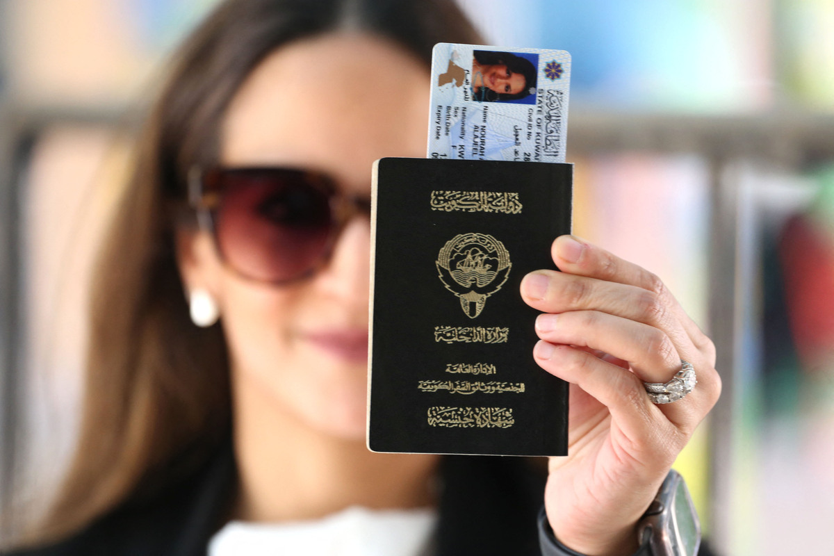 A Kuwaiti woman displays her passport as she votes during parliamentary elections in Kuwait City on September 29, 2022. Kuwait will holds its most inclusive elections in a decade today with some opposition groups ending a boycott after the oil-rich country's royal rulers pledged not to interfere with parliament. (Photo by Yasser Al-Zayyat / AFP)