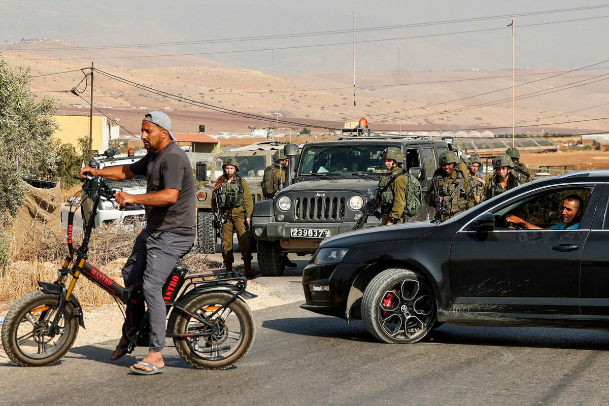 Israeli soldiers enforce the closure of a road near the site of an attack on an Israeli bus east of the Palestinian city of Tubas in the north of the occupied West Bank on September 4, 2022. Gunmen wounded six Israeli soldiers and a civilian on September 4 when they sprayed bullets at a bus in the occupied West Bank. The attack in the Jordan Valley, near the city of Tubas, comes amid a spate of violence in the West Bank in recent days and a shooting spree last month targeting an Israeli bus in annexed east Jerusalem. (Photo by JAAFAR ASHTIYEH / AFP)