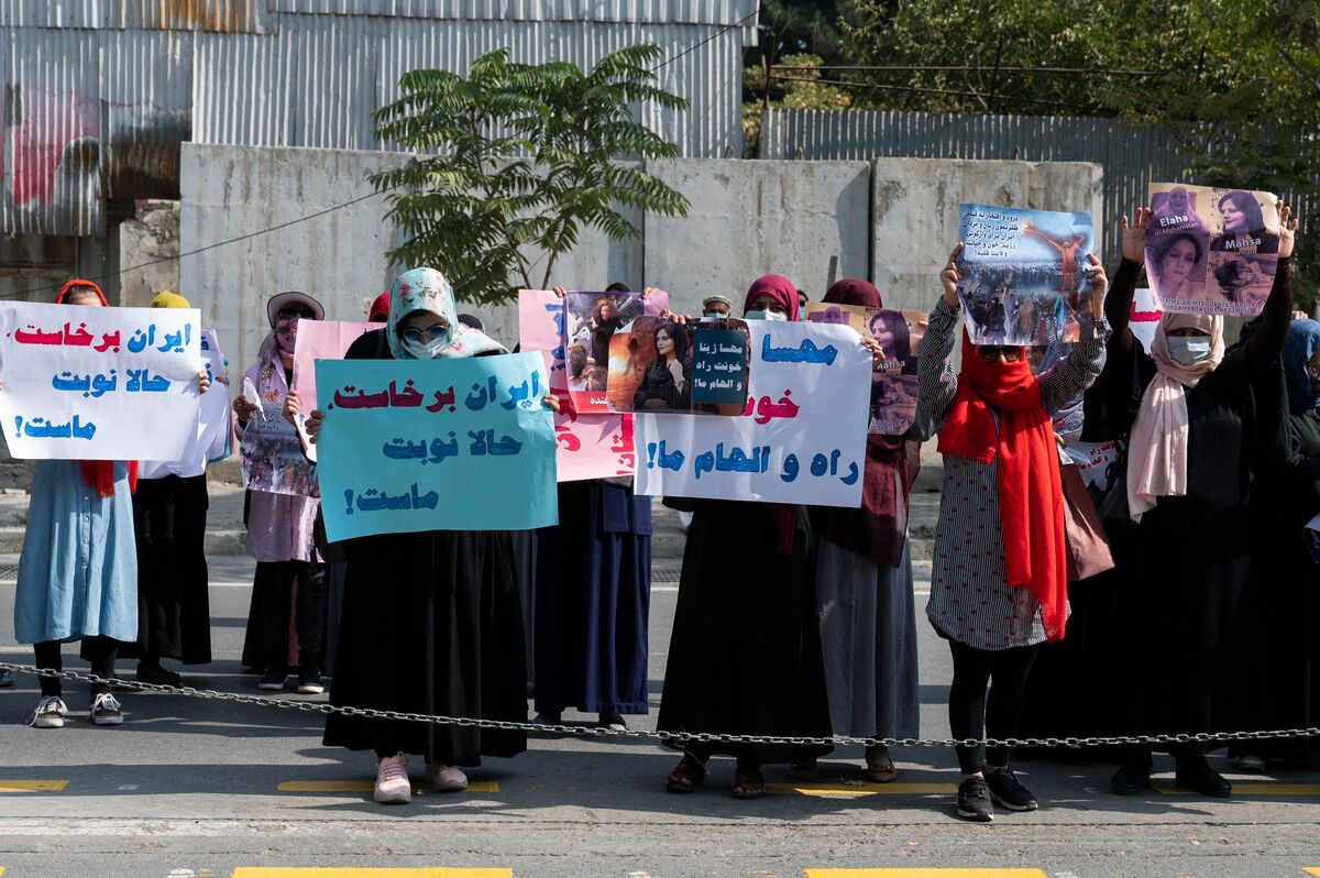 TOPSHOT - Afghan women hold placards as they take part in a protest in front of the Iranian embassy in Kabul on September 29, 2022. Taliban forces fired shots into the air on September 29 to disperse a women's rally supporting protests that have erupted in Iran over the death of a woman in the custody of morality police. (Photo by Wakil KOHSAR / AFP)