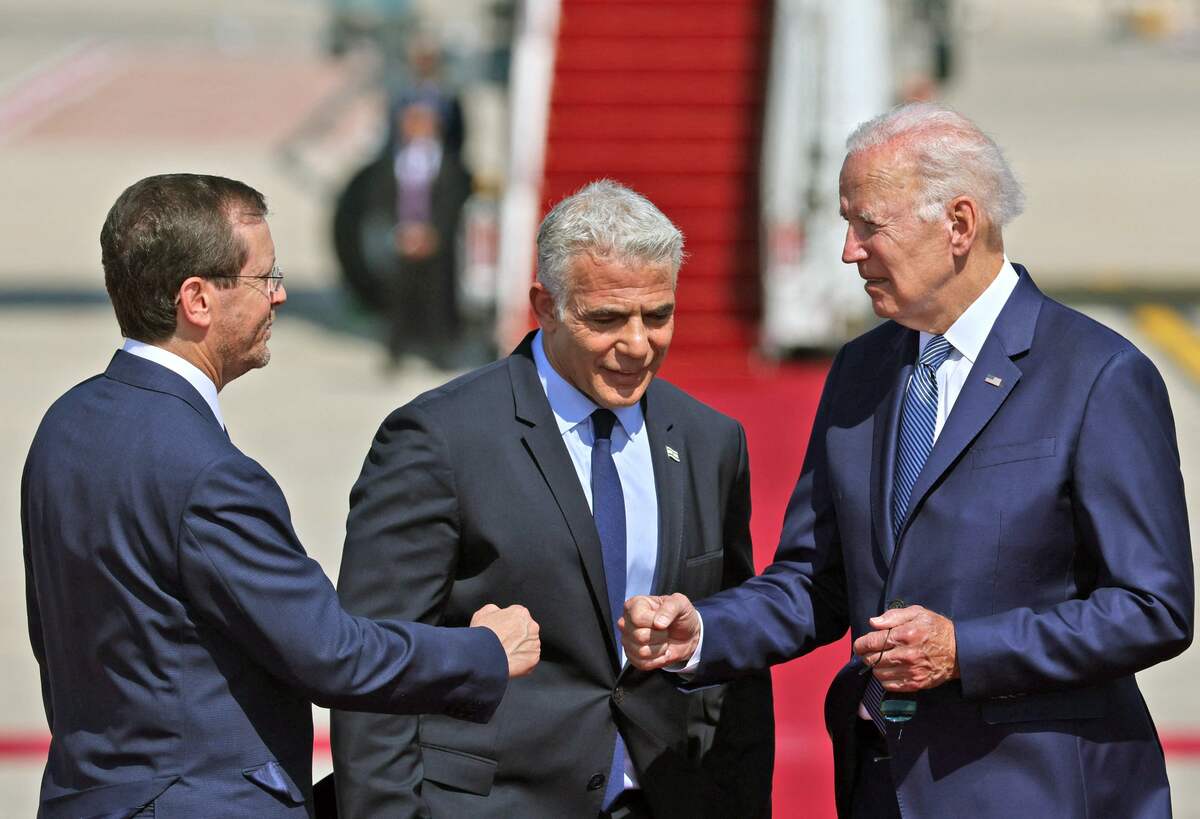 US President Joe Biden (R) bumps fists with Israel's President Isaac Herzog as caretaker Prime Minister Yair Lapid looks on, at Israel's Ben Gurion Airport in Lod near Tel Aviv, on July 13, 2022. (Photo by JACK GUEZ / AFP)