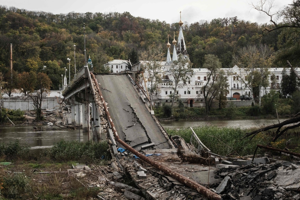 TOPSHOT - This photograph taken on October 9, 2022, shows a destroyed bridge over the Siverskyi Donets River remains near the Sviatohirsk Cave Monastery, "an Orthodox Christian monastery", partially damaged by shelling in the recently retaken town of Sviatohirsk in the Donetsk region, amid the Russian invasion of Ukraine. (Photo by Yasuyoshi CHIBA / AFP)