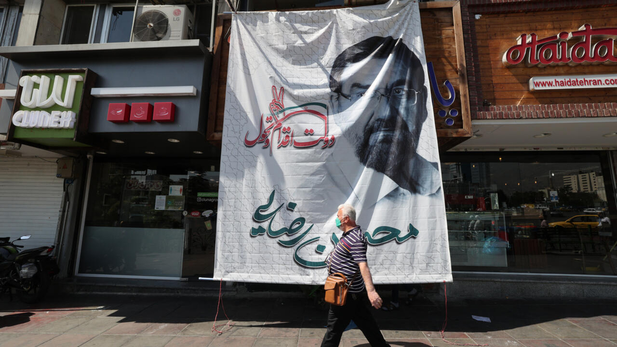 Iranians walk past under a huge poster depicting Iranian presidential candidate Mohsen Rezaie in a street in Tehran on June 15, 2021, ahead of the June 18 presidential elections.