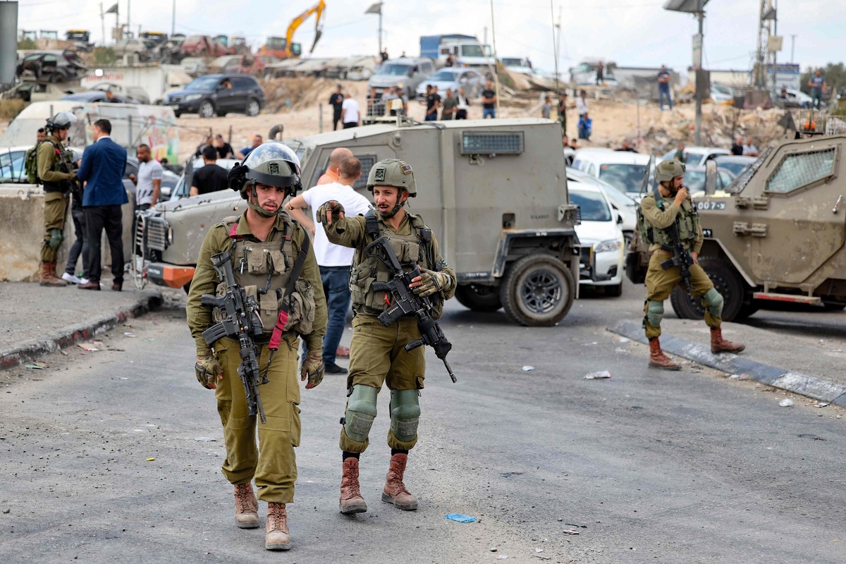 Israeli soldiers stand guard at one of the entrances of the Shuafat refugee camp in east Jerusalem on October 9, 2022, blocked oto traffic after an Israeli soldier was shot and killed in an overnight attack at a checkpoint near the camp. A police spokesperson had announced earlier that a manhunt was underway for an assailant who had "shot and severely injured two Israelis" at a checkpoint near the Palestinian refugee camp. A third person, whose nationality was not specified, was hit by "shrapnel", according to Magen David Adom (MADA), the emergency medical services that are Israel's equivalent of the Red Cross. (Photo by AHMAD GHARABLI / AFP)