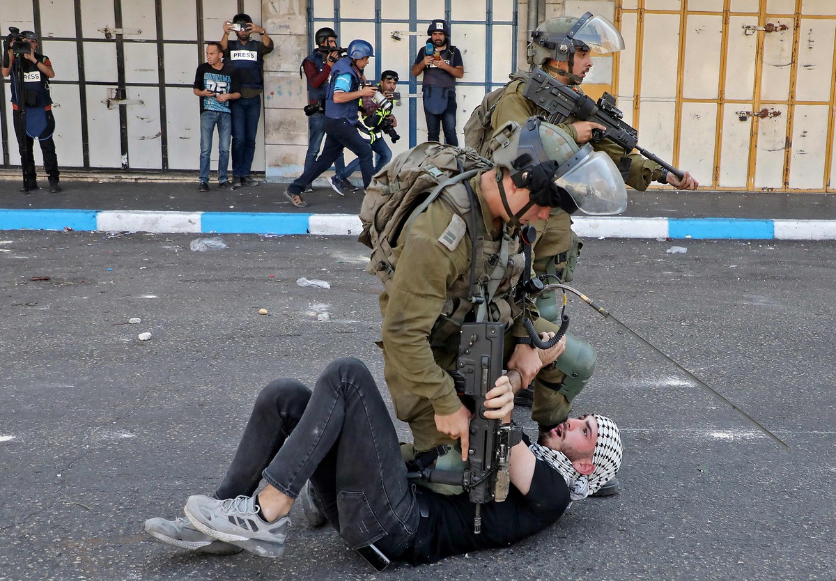 TOPSHOT - Israeli soldiers scuffle with a Palestinian during clashes in the flashpoint city of Hebron in the occupied West Bank on October 20, 2022. (Photo by MOSAB SHAWER / AFP)