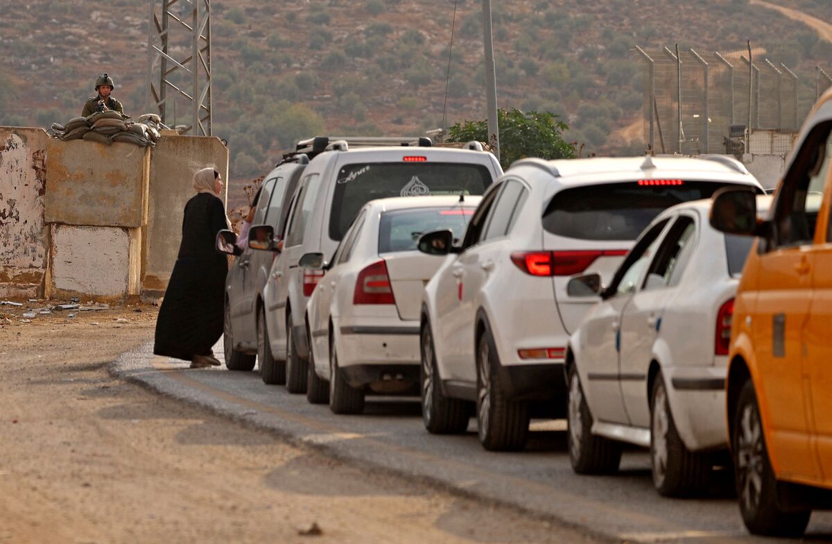 Palestinians wait in a long queue at an Israeli checkpoint between the Palestinian city of Nablus and the village of Beit Furik in the occupied West Bank on October 26, 2022, on the 15th day of a military lockdown following the killing of an Israeli soldier near the settlement of Shavei Shomron. (Photo by JAAFAR ASHTIYEH / AFP)