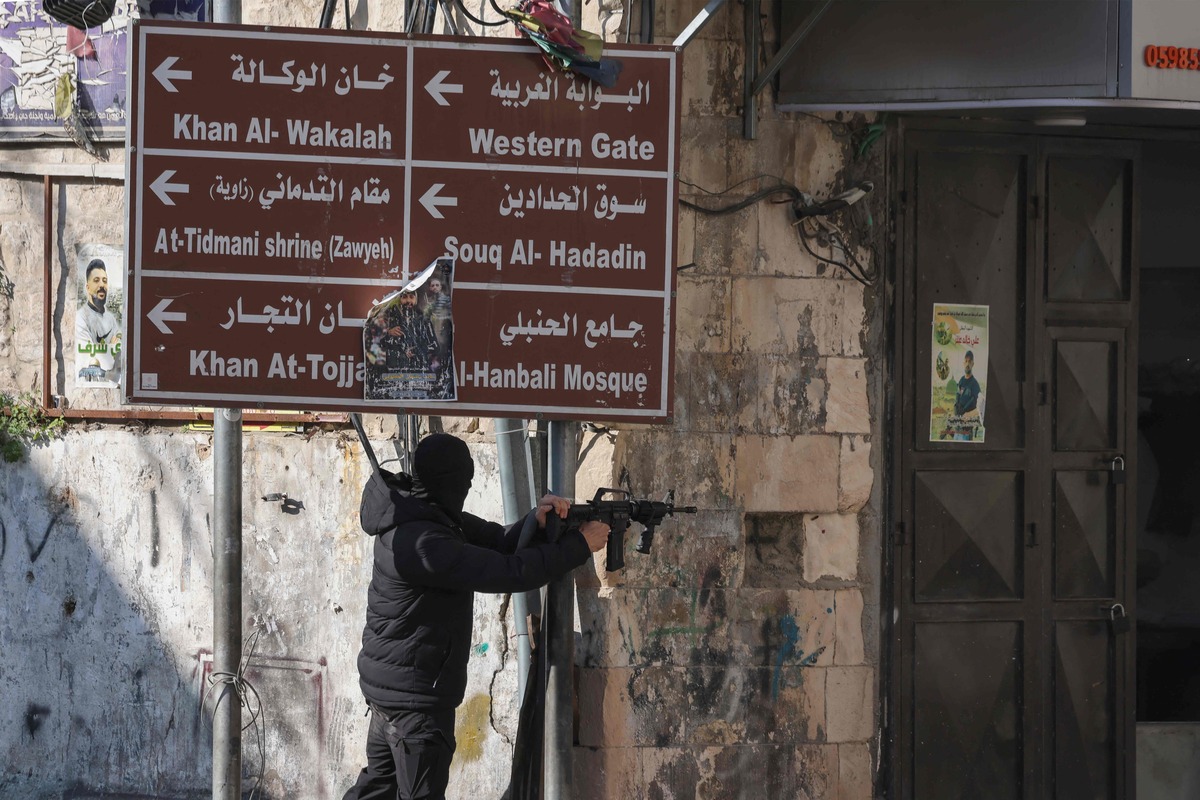 A Palestinian gunman fires his rifle amid clashes with Israeli security forces deploying during a raid in the old city of Nablus, in the occupied West Bank, on December 30, 2022. (Photo by Jaafar ASHTIYEH / AFP)