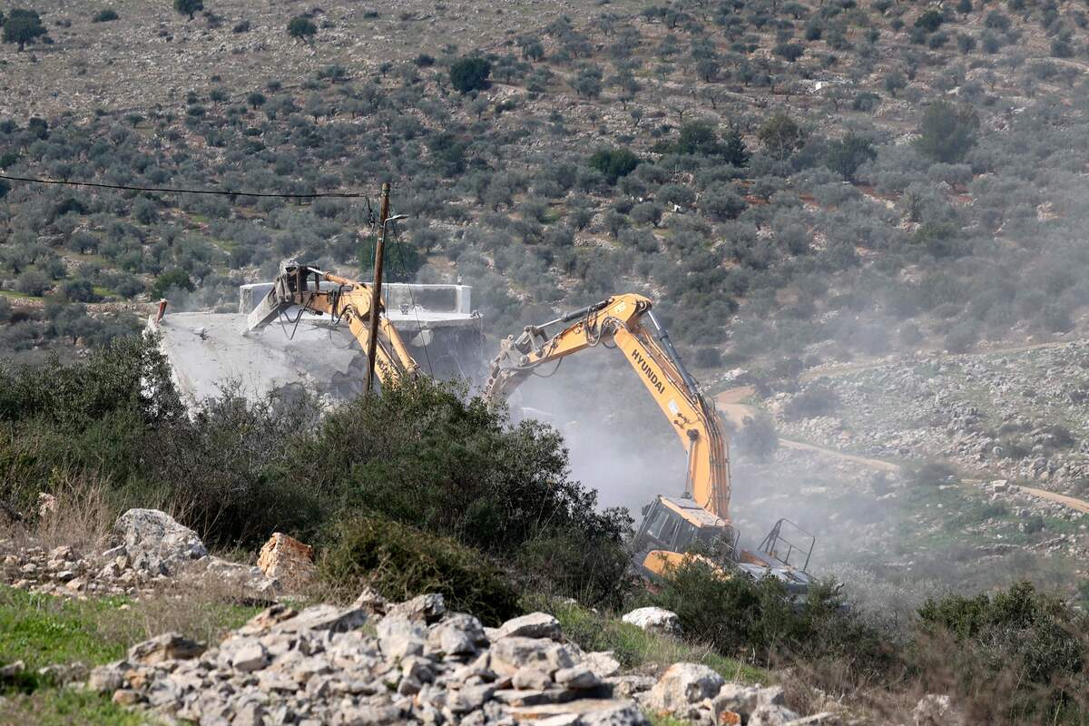 an Israeli security forces excavator demolishes a house in the Palestinian village of Kafr al-Dik west of Salfit city in the occupied West Bank, on January 10, 2023. (Photo by Jaafar ASHTIYEH / AFP)