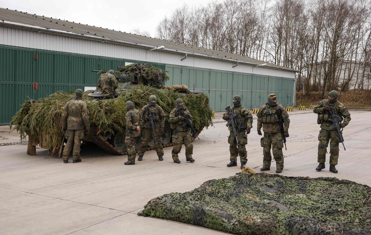 German soldiars stand around an camouflaged armoured "Marder" vehicle before the arrival of the German Defence Minister at a military base of an armored infantryman batallion in Marienberg, eastern Germany, on January 12, 2023. Germany will supply Ukraine with about 40 Marder infantry fighting vehicles within weeks as part of a new phase of support coordinated with the US. (Photo by Odd ANDERSEN / AFP)