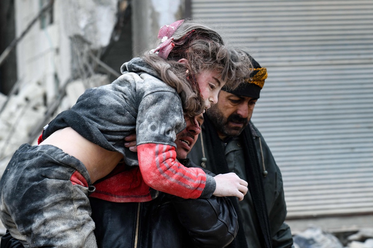 EDITORS NOTE: Graphic content / TOPSHOT - Residents carry an injured child from the rubble of a collapsed building following an earthquake in the town of Jandaris, in the countryside of Syria's northwestern city of Afrin in the rebel-held part of Aleppo province, on February 6, 2023. Hundreds have been reportedly killed in north Syria after a 7.8-magnitude earthquake that originated in Turkey and was felt across neighbouring countries. (Photo by Rami al SAYED / AFP)