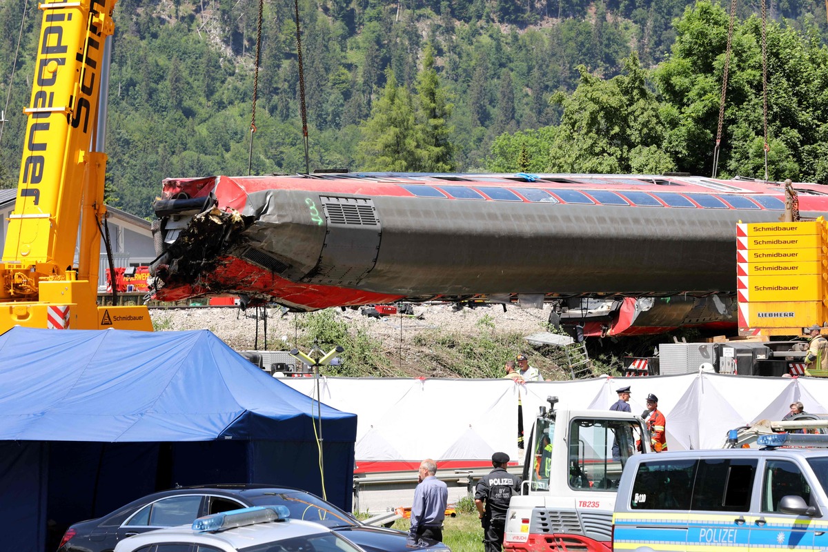 Workers use cranes to salvage a railway carriage at the site of a train derailment near Burgrain, north of Garmisch-Partenkirchen, southern Germany, on June 4, 2022, a day after the accident. A train derailed near a Bavarian Alpine resort in southern Germany on June 3, killing at least four people and injuring dozens in a region gearing up to host the G7 summit in late June. (Photo by Dominik BARTL / AFP)