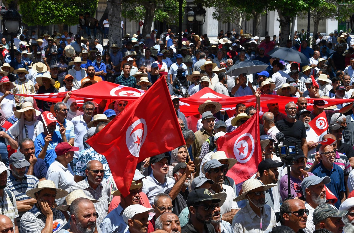 Tunisian protesters lift national flags during a demonstration in the capital Tunis on June 19, 2022, against President Kais Saied and the upcoming July 25 constitutional referendum. (Photo by FETHI BELAID / AFP)