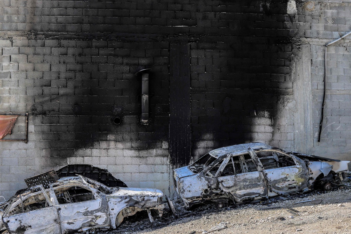 This picture taken on February 27, 2023 shows a view of torched cars and a building in the town of Huwara near Nablus in the occupied West Bank. Two Israelis living in the Har Bracha settlement near Nablus were killed on February 26 in a "Palestinian terror attack", officials said, sparking violence in which a Palestinian man was killed, while settlers torched homes in revenge. (Photo by RONALDO SCHEMIDT / AFP)