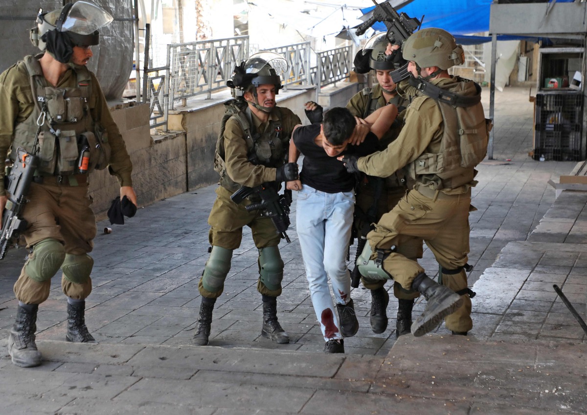 Israeli soldiers detain a Palestinian youth during clashes in the city of Hebron in the occupied West Bank on October 25, 2022. (Photo by MOSAB SHAWER / AFP)