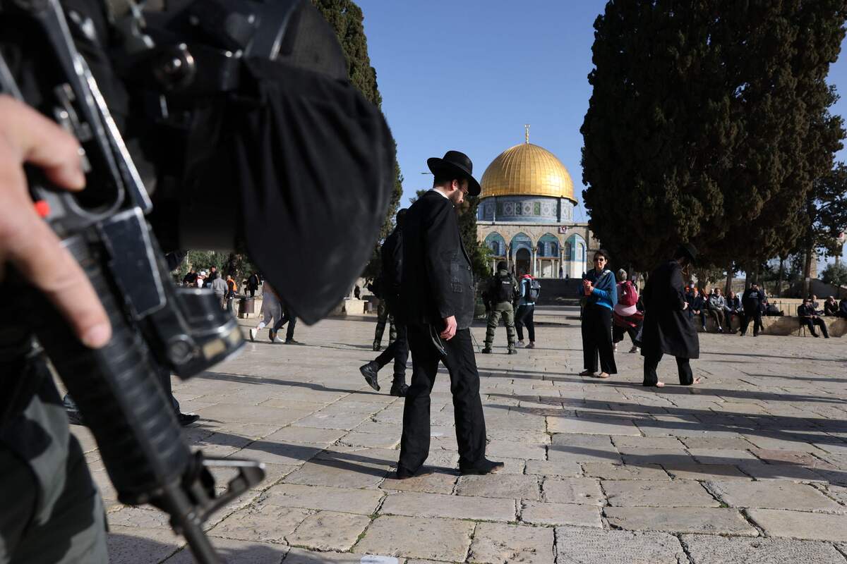 A religious Jewish man walks protected by Israeli security forces at the Al-Aqsa mosque compound in Jerusalem, early on April 5, 2023 during Islam's holy month of Ramadan. Israeli police said they had entered to dislodge "agitators", a move denounced as an "unprecedented crime" by the Palestinian Islamist movement Hamas. The holy Muslim site is built on top of what Jews call the Temple Mount, Judaism's holiest site. (Photo by AHMAD GHARABLI / AFP)