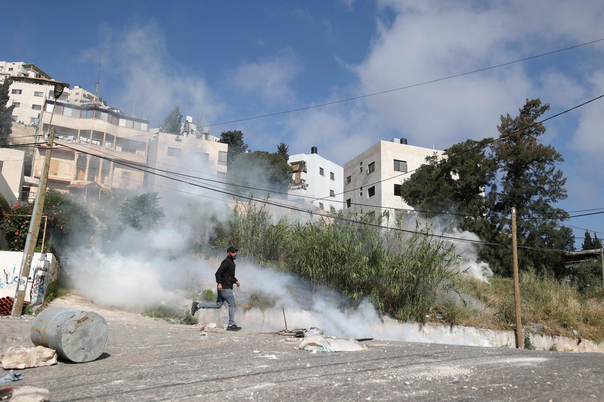 A Palestinian protester runs past billowing tear gas amid clashes with Israeli security forces during a reported raid in the old city of Nablus, in the occupied West Bank, on May 9, 2023. The Israeli army said it killed three leaders of the Islamic Jihad militant group on May 9 in air strikes on Gaza, which left a dozen dead according to the Palestinian territory's Hamas-controlled health ministry, adding that women and children were among the dead. (Photo by JAAFAR ASHTIYEH / AFP)